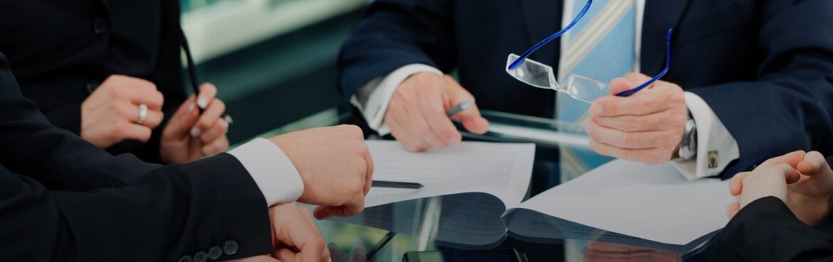 People in business suits with paperwork at desk
